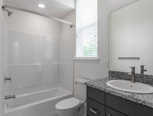 A white bathroom with a toilet, sink, and bathtub.