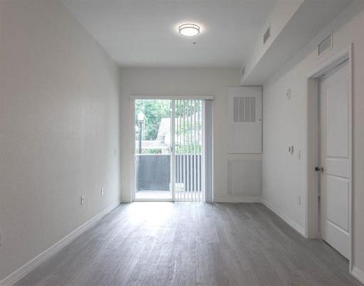 A room with a sliding glass door leading to a balcony.