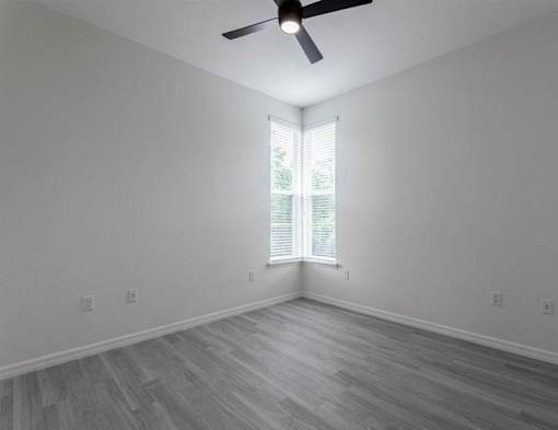 A room with a ceiling fan and a window with blinds.
