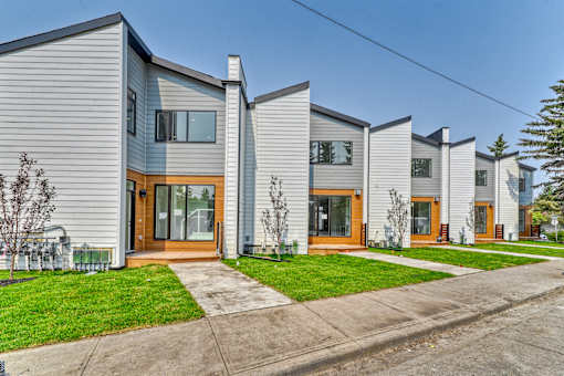 A row of modern houses with grey siding and wooden doors.