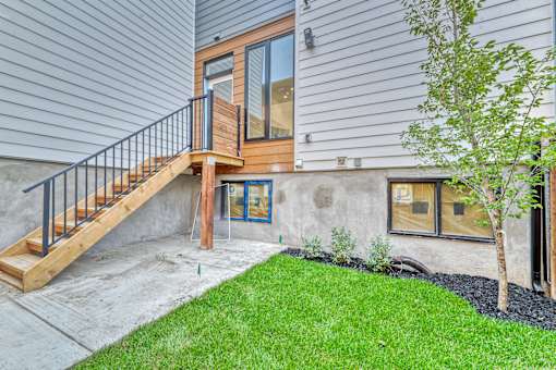 A house with a wooden deck and a tree in front.