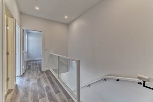 A hallway with a wooden floor and white walls.