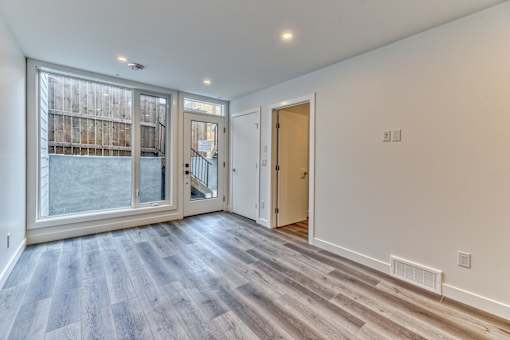 A room with a wooden floor and a glass door leading to a balcony.