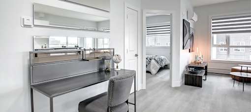 A modern bedroom with a large mirror above a vanity table.