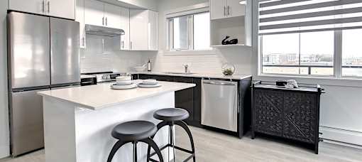 A modern kitchen with a white countertop and stainless steel appliances.