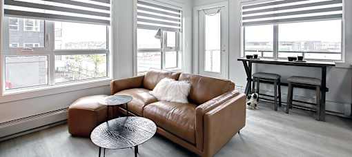 A brown leather couch with a round table in front of it.