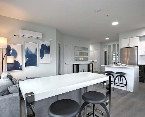 A modern kitchen with a white island and bar stools.