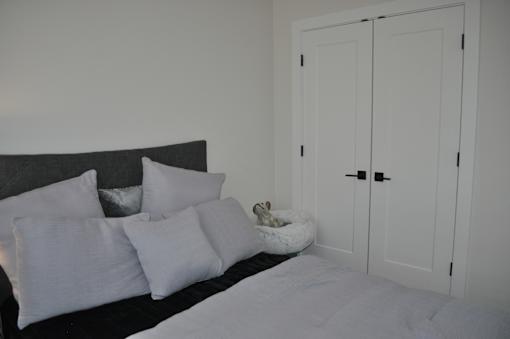A bed with white pillows and a cat bed with a cat in it at The Laurent at Laurel Apartments, Edmonton