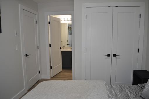 A bedroom with a bed, a mirror, and a dresser at The Laurent at Laurel Apartments, Edmonton, T6T 2T5