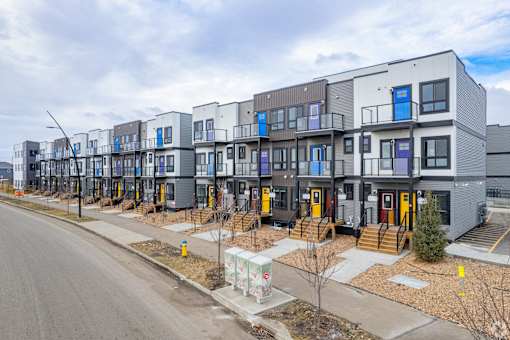 A row of modern townhouses with balconies and front yards.at The Pointe at Riverview, Alberta