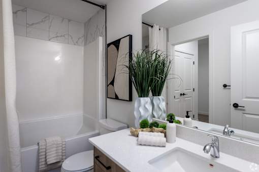 A white bathroom with a white toilet and a white sink.at The Pointe at Riverview, Edmonton, T6M 3H4