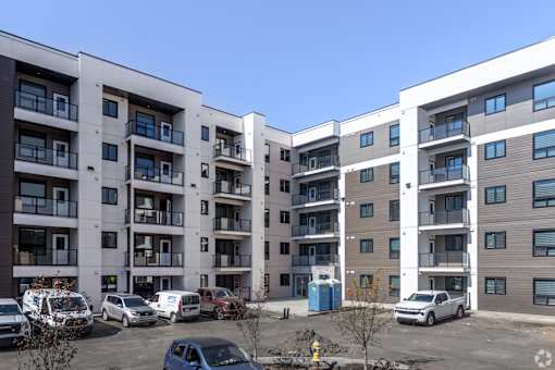 A parking lot with cars and apartment buildings in the background.at The Pointe at Riverview, Edmonton, AB T6M 3H4