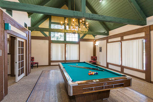 A pool table in a room with wooden floors and a chandelier.