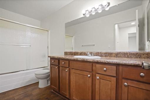 A bathroom with a toilet, sink, and wooden cabinets.
