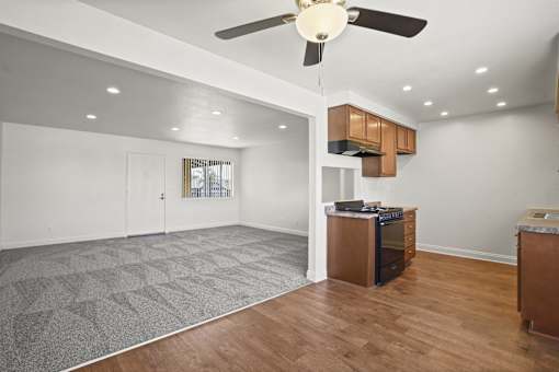 A spacious kitchen with a ceiling fan and wooden floors.