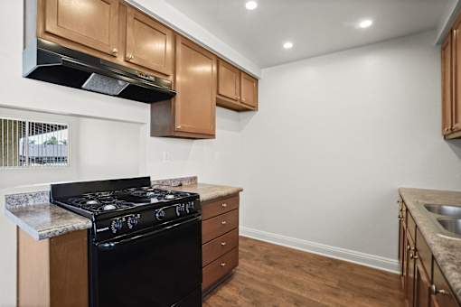 A kitchen with a black stove top oven and wooden cabinets.