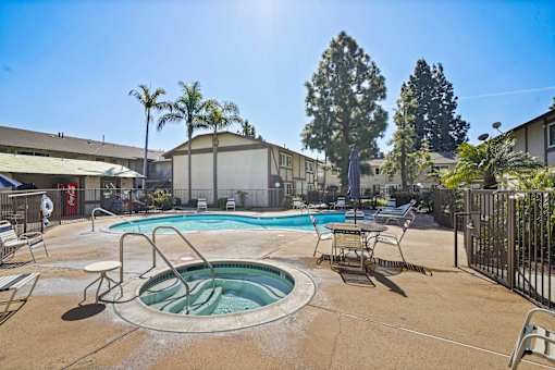 A pool surrounded by chairs and trees.