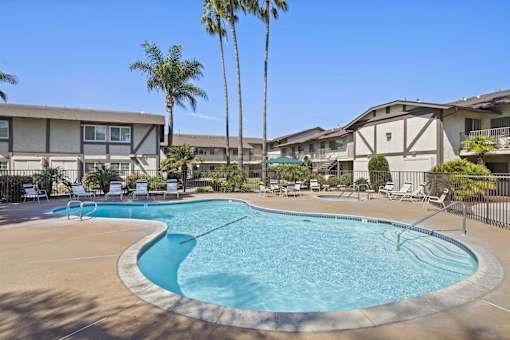 A swimming pool surrounded by palm trees and lounge chairs.