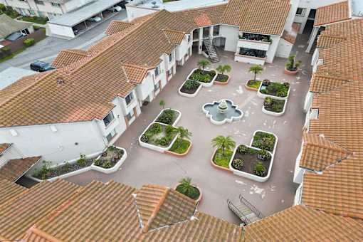 A courtyard surrounded by buildings with a fountain in the middle.