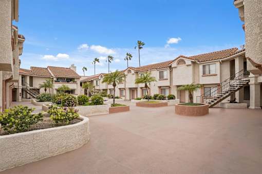 A sunny day at a residential complex with houses and palm trees.