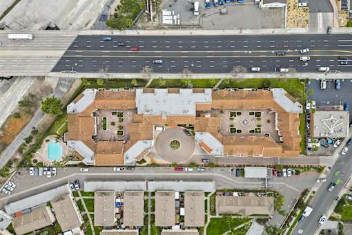 A large building with a circular courtyard in the middle is surrounded by smaller buildings and a busy road.