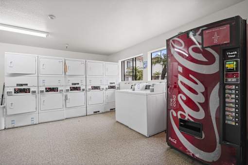 A Coca-Cola vending machine is in a room with white cabinets.