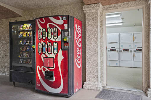 A Coca-Cola vending machine sits next to a white door.