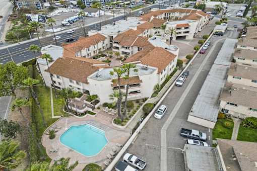 A swimming pool is surrounded by a building with a red tile roof.