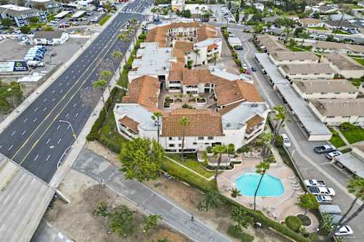 A bird's eye view of a residential area with a swimming pool and a road running through it.