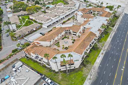 A large building with a red roof is surrounded by a parking lot.