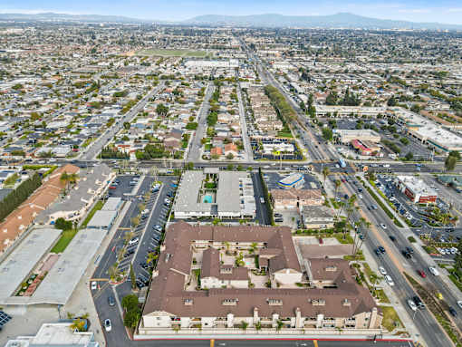 A large, open parking lot is surrounded by apartment buildings and a busy road.