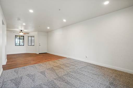 A room with a ceiling fan and a rug on the floor.