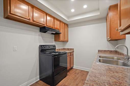 A kitchen with a black stove top oven and wooden cabinets.