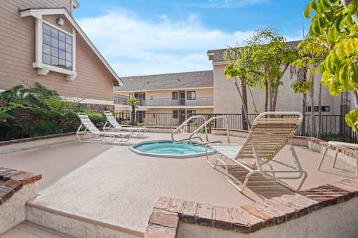 A pool with a hot tub and chairs in front of a house.