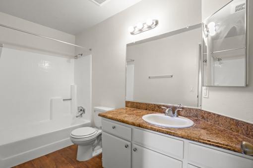 A bathroom with a sink, toilet, and mirror.