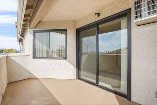 A balcony with a glass door and window.