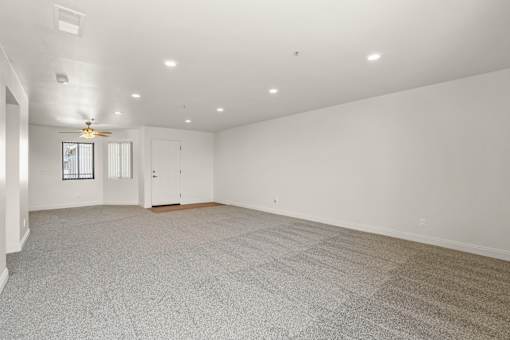 A spacious room with a carpeted floor and a ceiling fan.