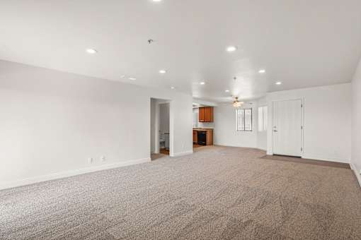 A large, empty room with a carpeted floor and white walls.