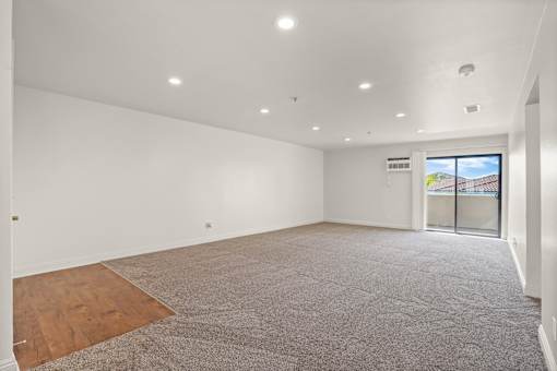 Empty room with carpeted floor and sliding glass door.