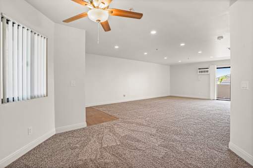 A spacious room with a ceiling fan and carpeted floor.