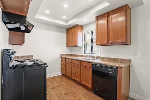 A kitchen with a black stove top oven and wooden cabinets.