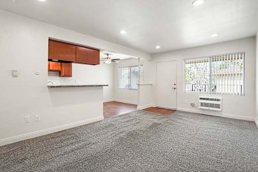 A spacious living room with a grey carpet and white walls.