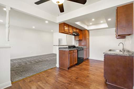 A kitchen with wooden cabinets and a white ceiling fan.