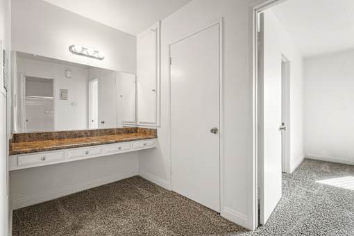 A white bathroom with a vanity and a mirror.