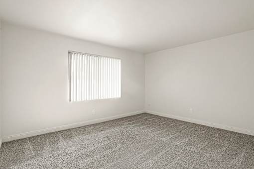 A room with a carpeted floor and a window with blinds.