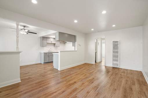 A spacious room with wooden flooring and a ceiling fan.