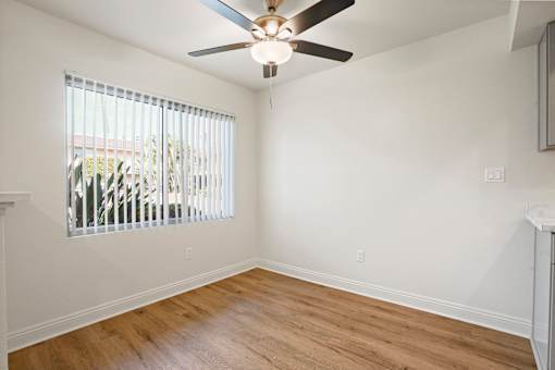 A room with a ceiling fan and a window with blinds.
