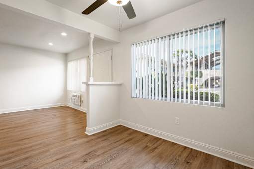 A room with a window covered by white blinds and a ceiling fan.