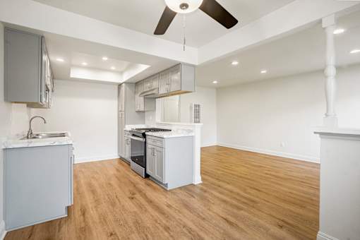 A kitchen with white cabinets and a wooden floor.