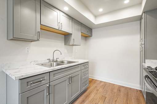 A kitchen with a marble countertop and grey cabinets.